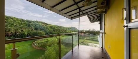 A balcony with a view of a green landscape and a clear sky.