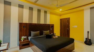 A bedroom with a large bed, a wooden headboard, a guitar, and a nightstand with a lamp.