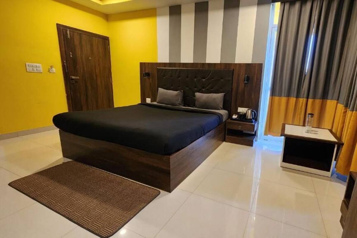 Een moderne hotelkamer met een groot bed, nachtkastje en een raam met gordijnen.