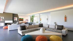 Ein modernes Wohnzimmer mit einer Eckcouch, einem Couchtisch und bunten Poufs.