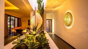 Ein modernes Interieur mit einem Kaktus als Blickfang, einem Essbereich und einer Wand mit einer runden Leuchte.