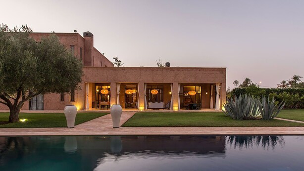 Ein modernes Haus mit Pool, großen Vasen und einem gepflegten Rasen.