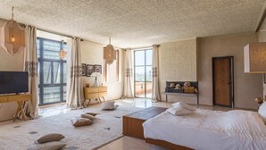 Ein geräumiges Schlafzimmer mit einem großen Bett, einem Schreibtisch und einem Fernseher.