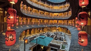 A traditional multi-level courtyard with wooden architecture, lanterns, and a central seating area.