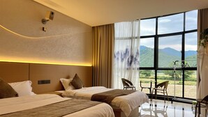 A hotel room with two beds, a large window with a mountain view, a small table, and a chair. - Wangxian Valley Qingchuanxingguan - Wangxian Valley Scenic Area  (Shangrao)