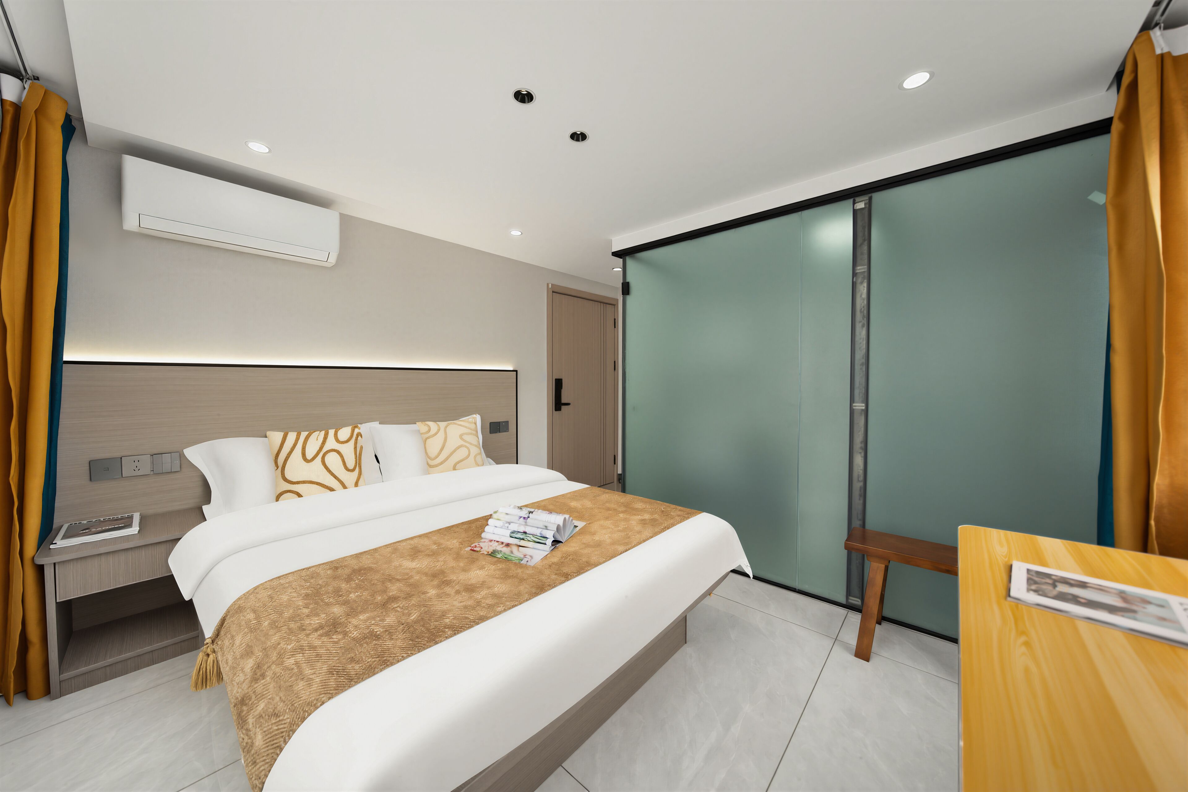 A modern hotel room with a bed, bedside table, and a sliding glass door leading to a balcony.