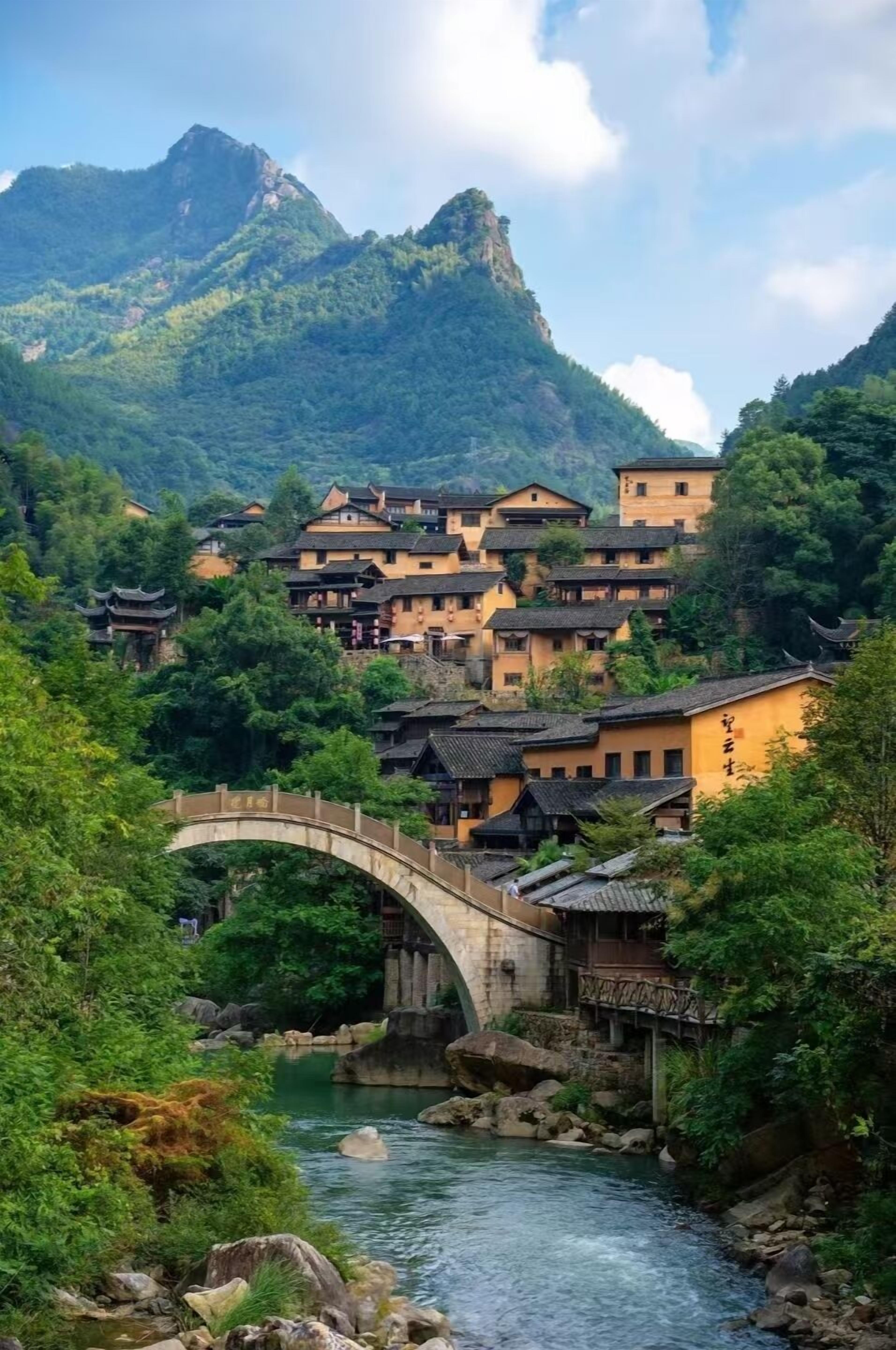 A traditional village with stone buildings, a stone bridge, and a river.