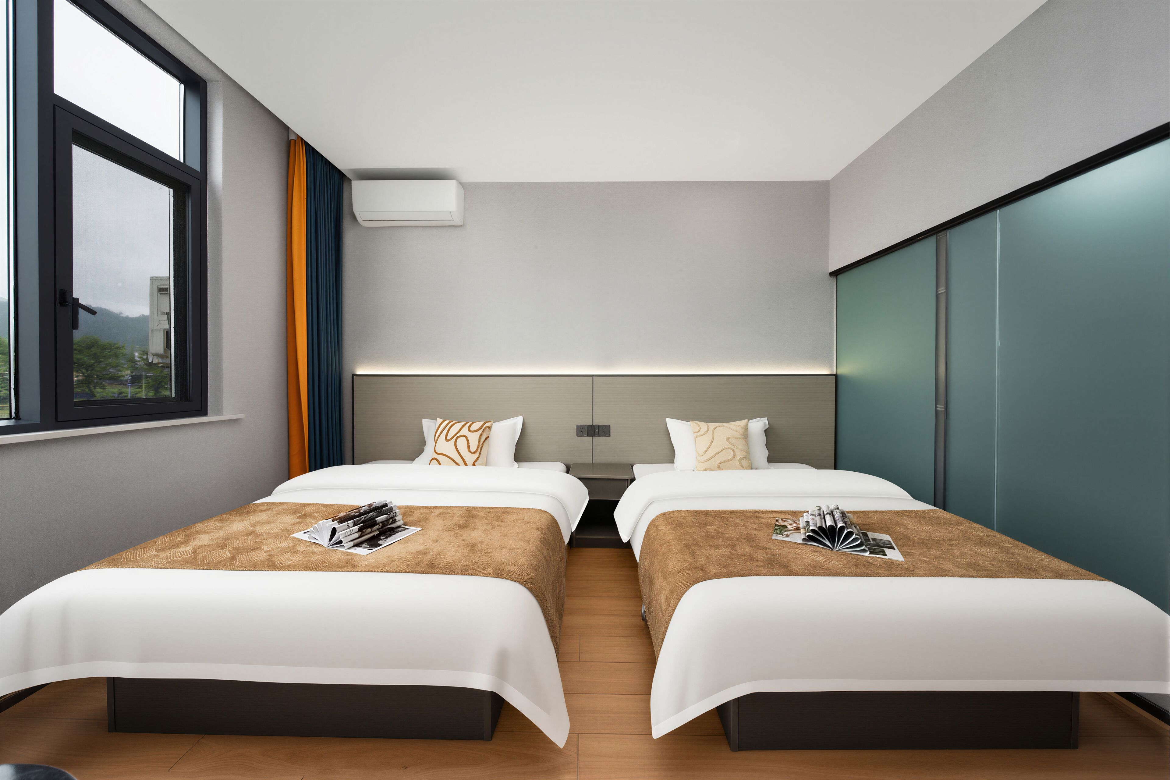 Habitación de hotel con dos camas, un ventanal amplio, aire acondicionado de pared y vista a la ciudad.