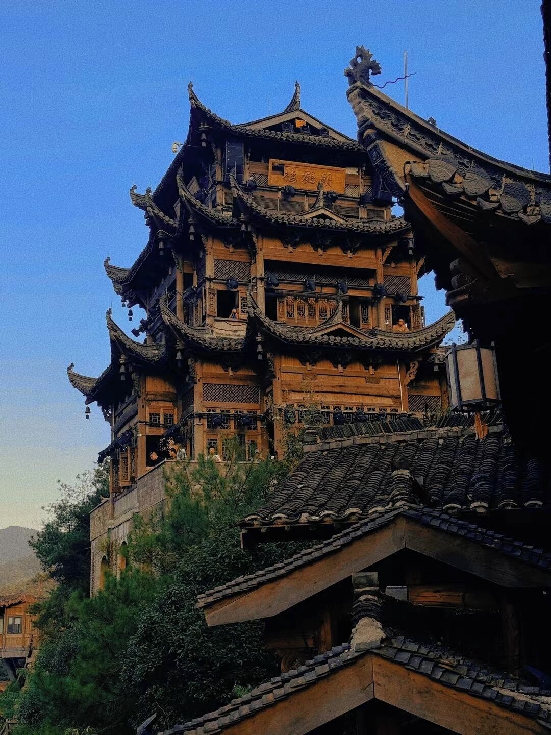 Un edificio tradicional de madera con varios niveles, detalles arquitectónicos ornamentales y un techo empinado.