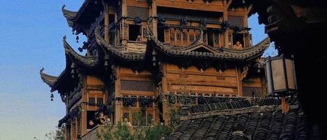 Un edificio tradicional de madera con varios niveles, detalles arquitectónicos ornamentales y un techo empinado.