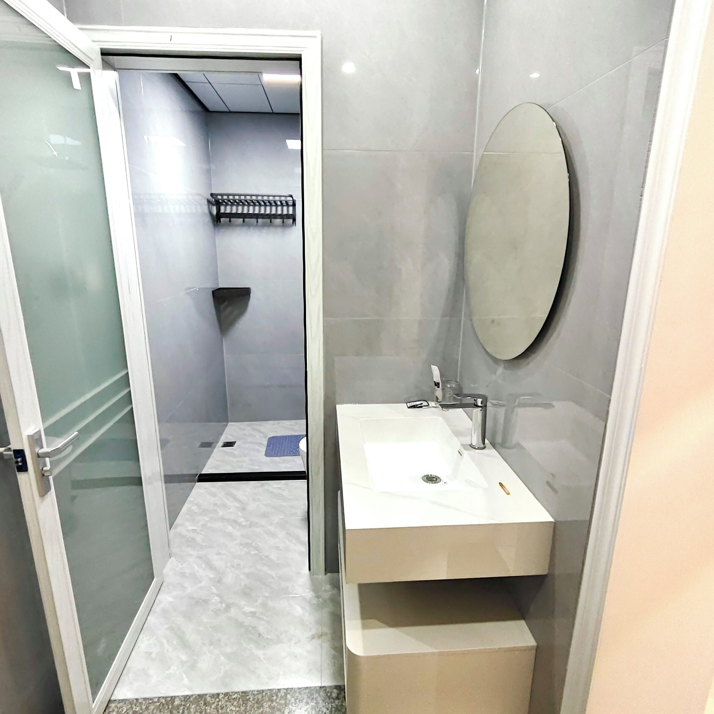 Un baño pequeño con un lavamanos blanco, un espejo y una zona de ducha.