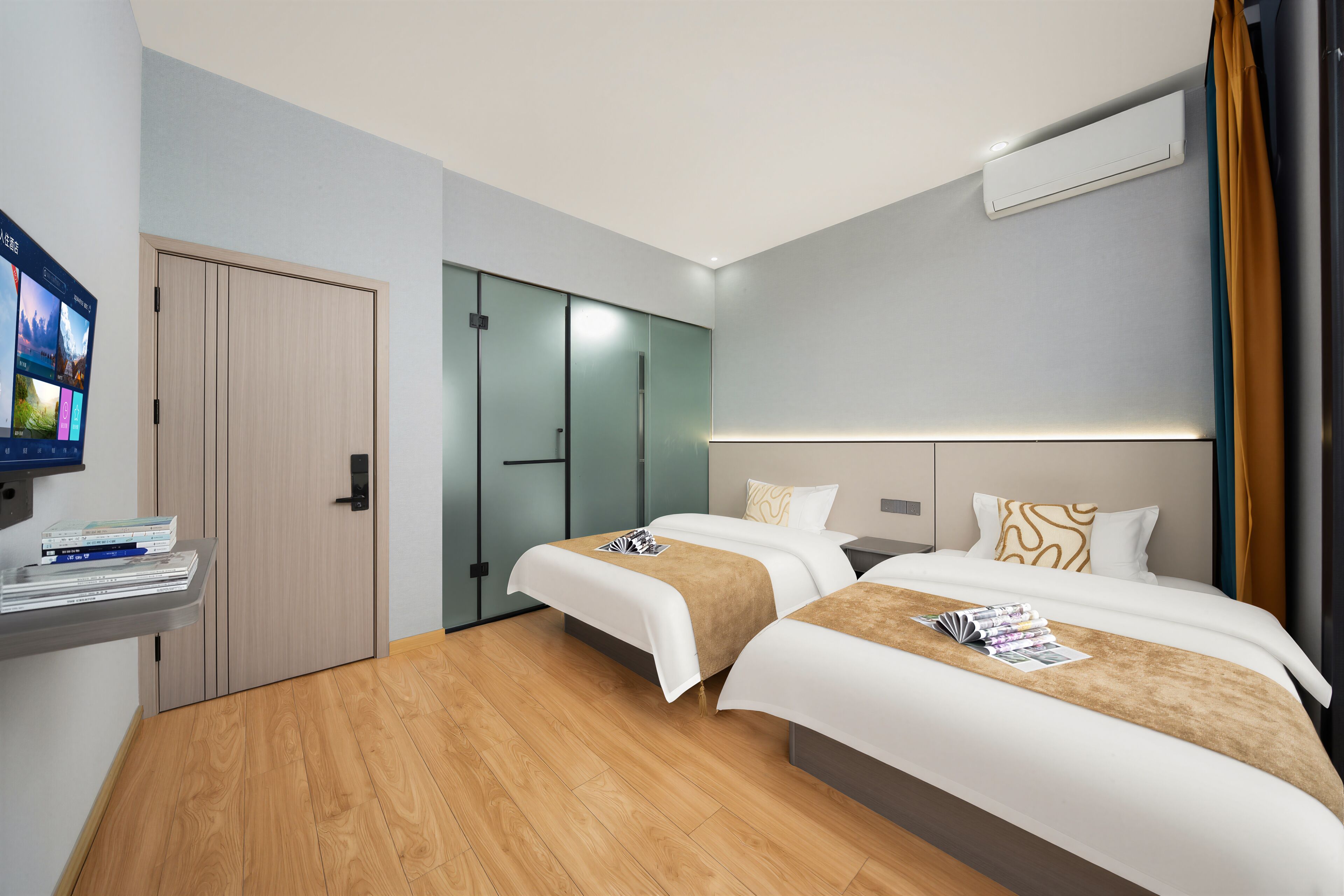 A hotel room with two beds, a TV, a shelf with books, and a wardrobe.