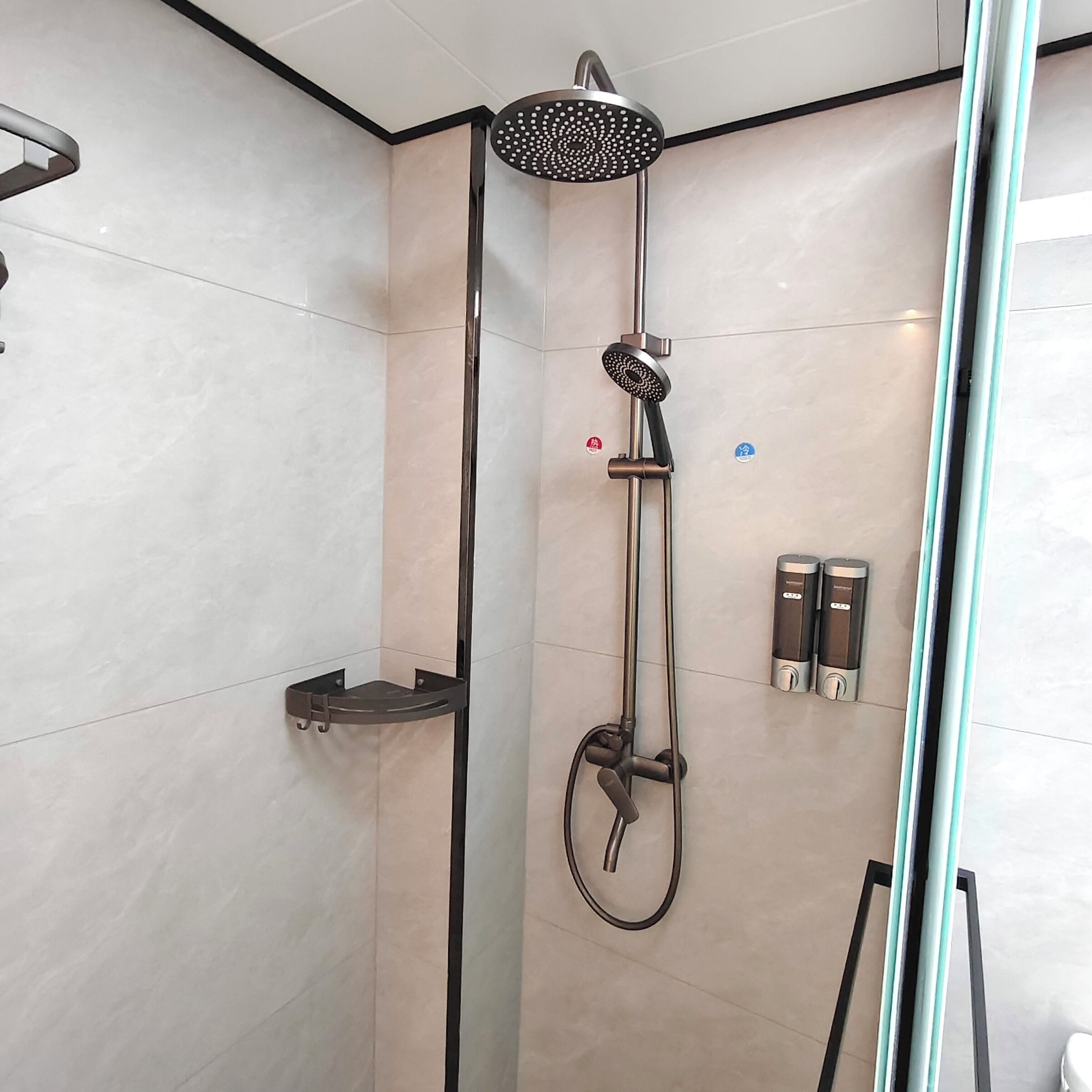 A modern shower with a handheld showerhead, a handheld rain shower attachment, and a wall-mounted control panel.