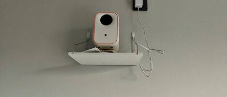Una estantería blanca con un altavoz blanco, montada en una pared lisa.
