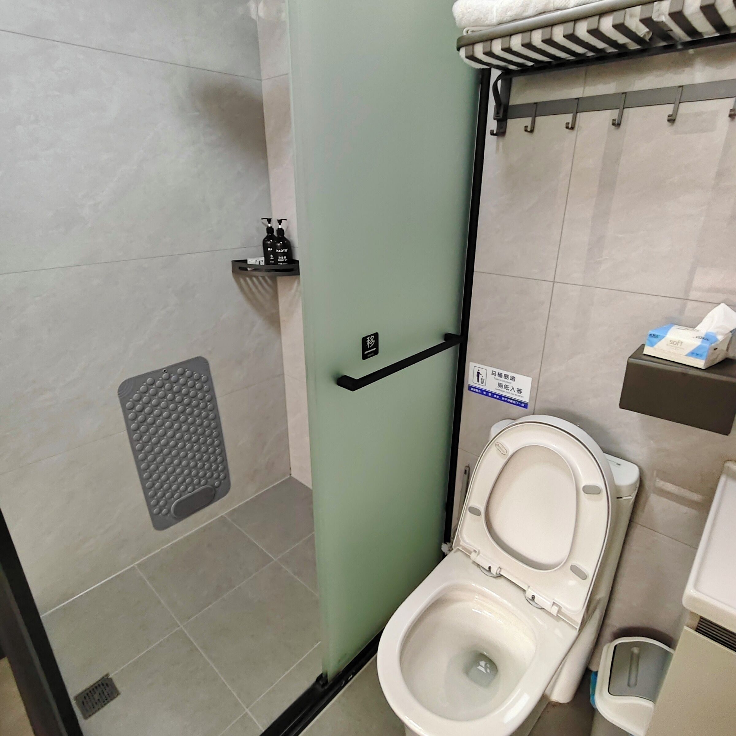 Un baño con inodoro, zona de ducha y secador de manos.