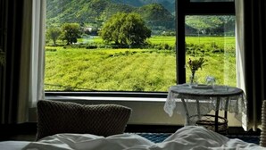 A bedroom with a large window offering a view of a green landscape and mountains. - Wangxian Valley Qingchuanxingguan - Wangxian Valley Scenic Area  (Shangrao)