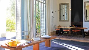 A room with a wooden bench, a dining table with chairs, a large window with curtains, and a mirror on the wall. - My Rental Homes - Villa Susan with heated pool and large garden (Marrakesh)