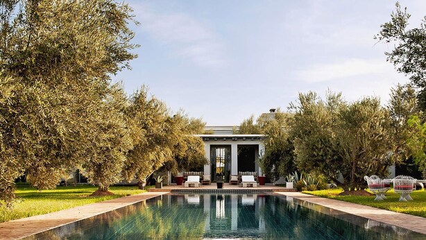 A pool with a clear view of the surrounding garden and a building with a covered seating area. - My Rental Homes - Villa Susan with heated pool and large garden (Marrakesh)
