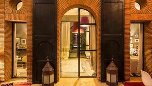 Een hotelentree met een bakstenen boog, grote deuren en twee lantaarns.