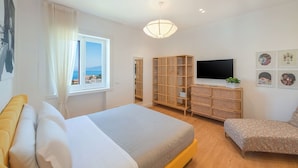 A bedroom with a bed, a TV, a wardrobe, and a window with a view of the sea. - Casa Mario with terrace and sea view (Sorrento)