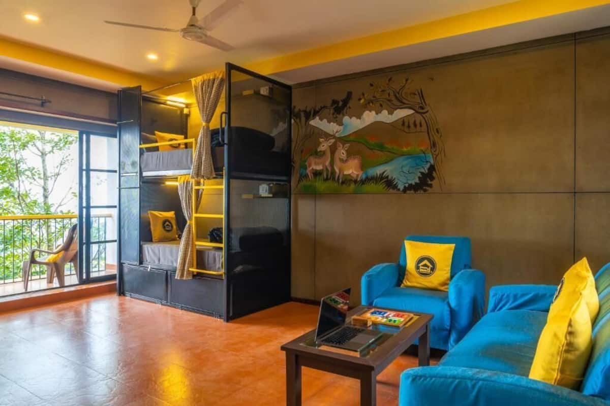 A room with a bunk bed, a blue sofa, a coffee table, and a mural on the wall.