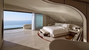 Une chambre spacieuse avec un plafond voûté, un grand lit, un banc et une vue sur la mer.