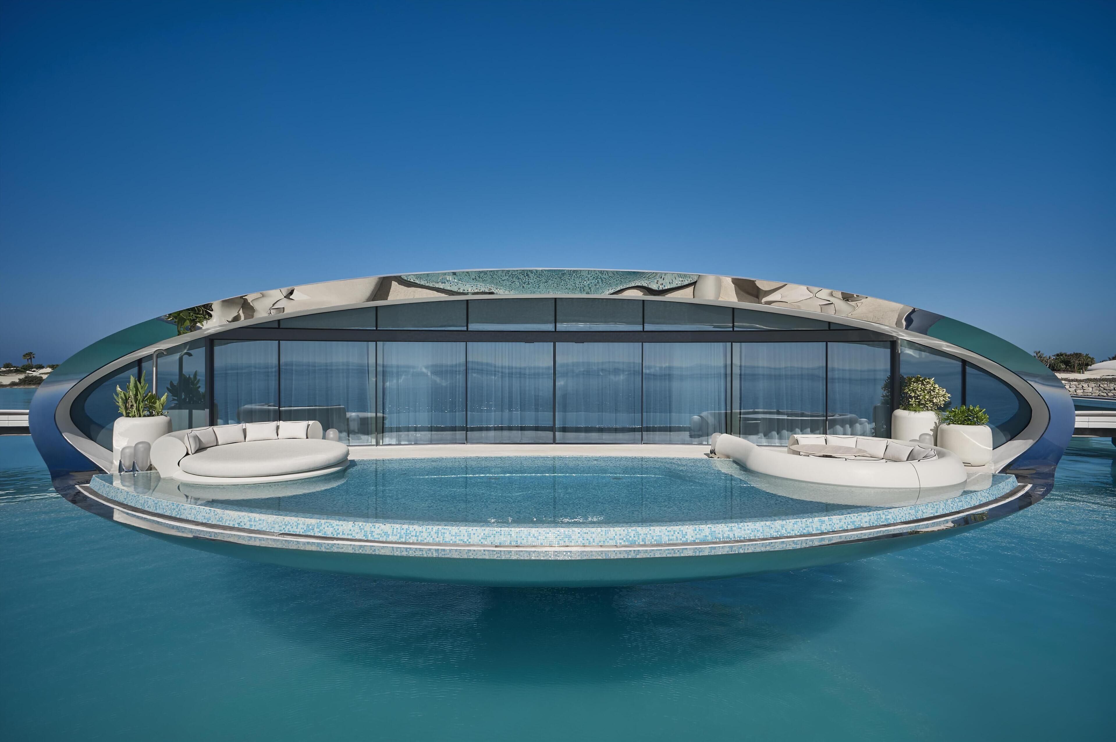 Una piscina infinita moderna con asientos integrados y cerramiento de vidrio.