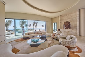 A modern living room with a large glass window, a stone wall, and a round wooden table. - Shebara Resort (Umluj)