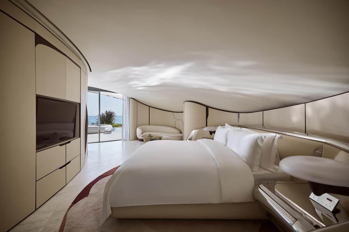 Una habitación de hotel moderna con una cama grande, televisión, sofá y vistas al exterior.
