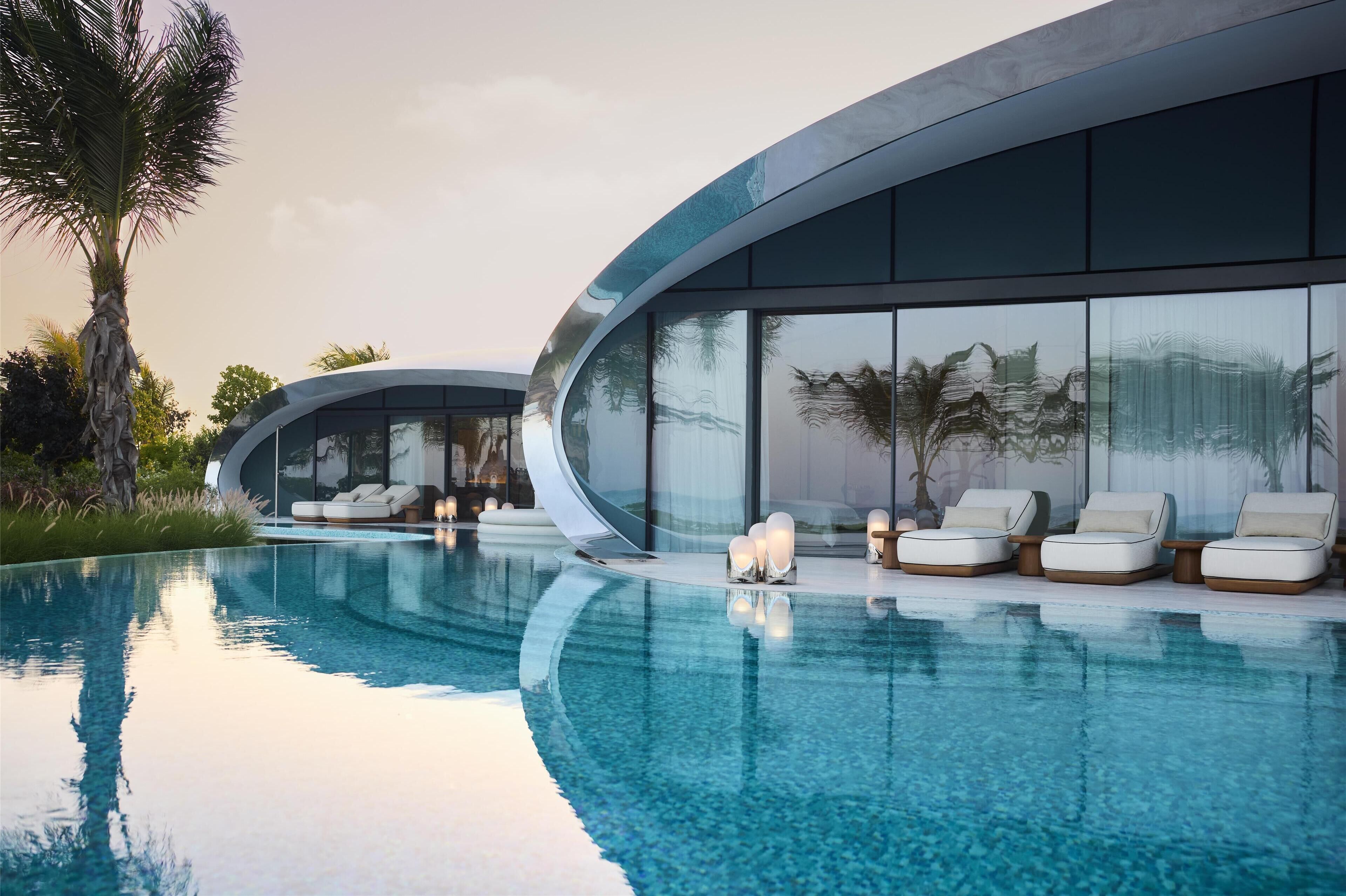Un área de piscina moderna con sillones de descanso y una estructura de vidrio.