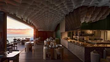 Ein modernes Restaurant mit einzigartigem Deckenstil, Blick auf den Sonnenuntergang und einer Bar.
