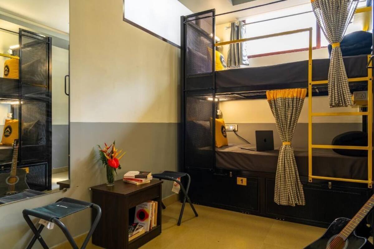 A bunk bed room with a desk, a guitar, and a small stool.