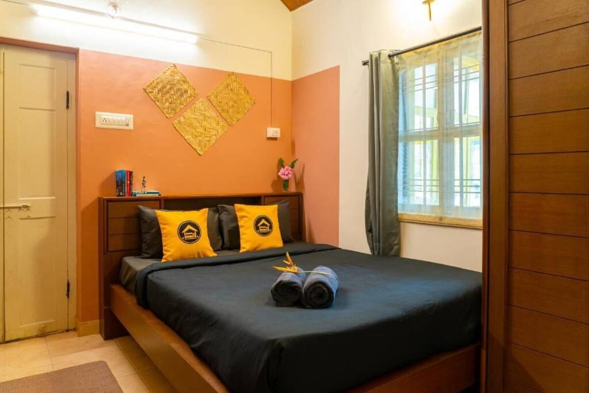 A bedroom with a bed, pillows, a nightstand, a window with curtains, and a wall decoration.