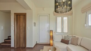 A modern living room with a sofa, a coffee table, and a chandelier. - Mili Serenity (Rethymno)