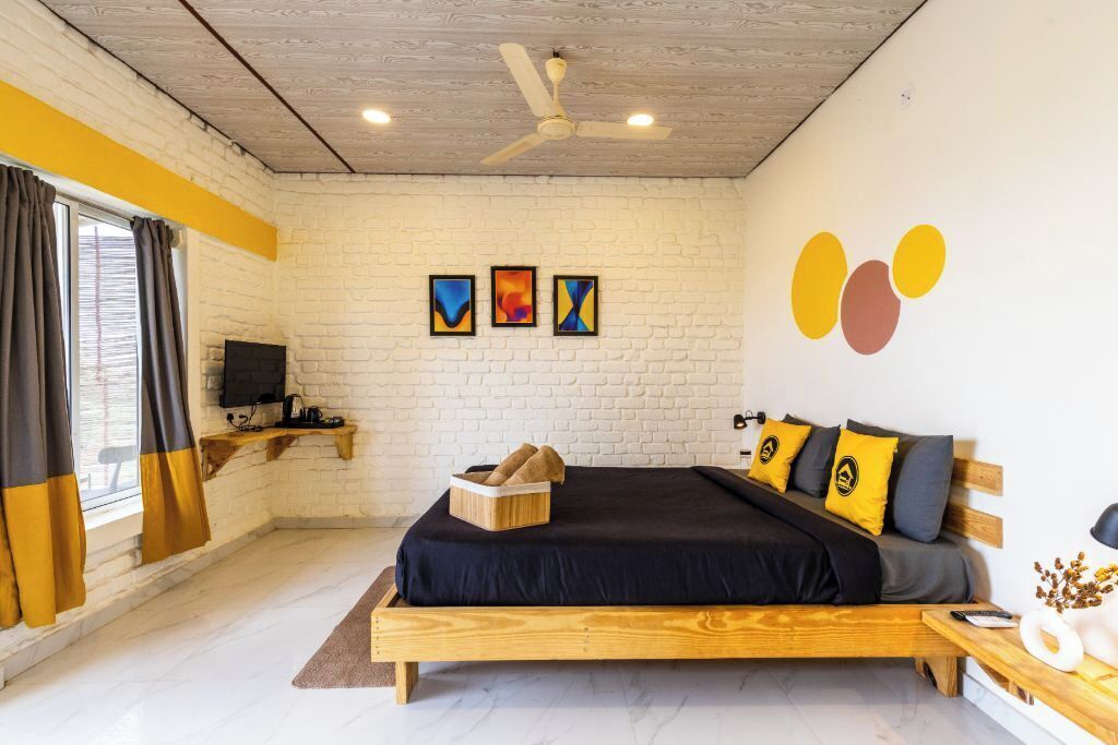 Quarto com cama de madeira, ventilador de teto, televisão e obras de arte na parede.