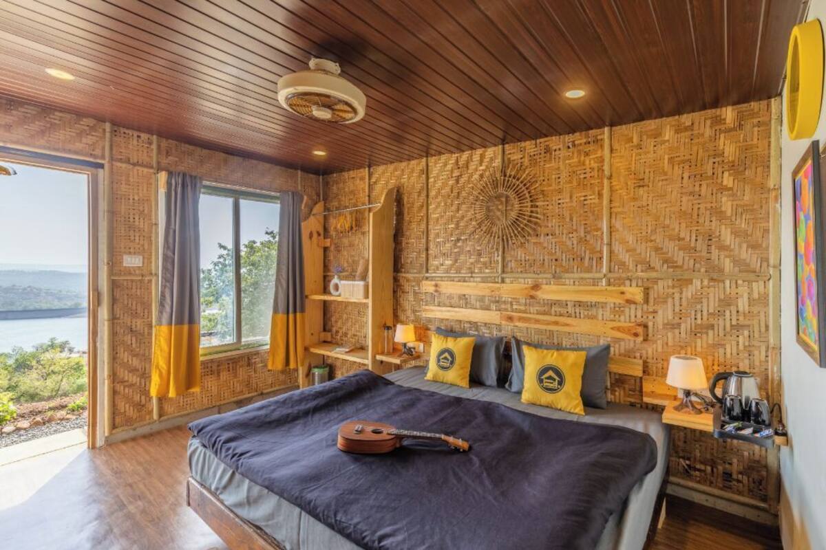 Un dormitorio con una cama grande, una guitarra, vista al exterior y un diseño de pared de madera.