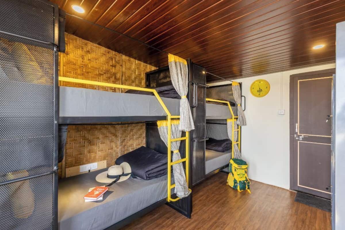 Habitación con literas, techo de madera, un reloj en la pared y una puerta.