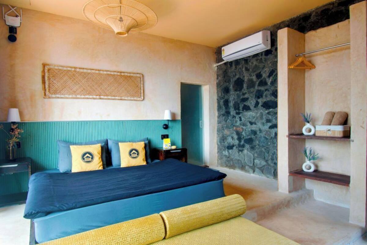 Un dormitorio con cama, una mesita de noche, aire acondicionado de pared y una pared de piedra.