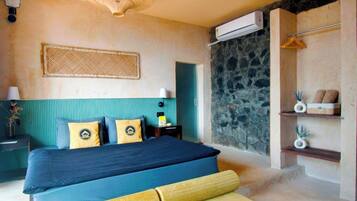 Un dormitorio con cama, una mesita de noche, aire acondicionado de pared y una pared de piedra.