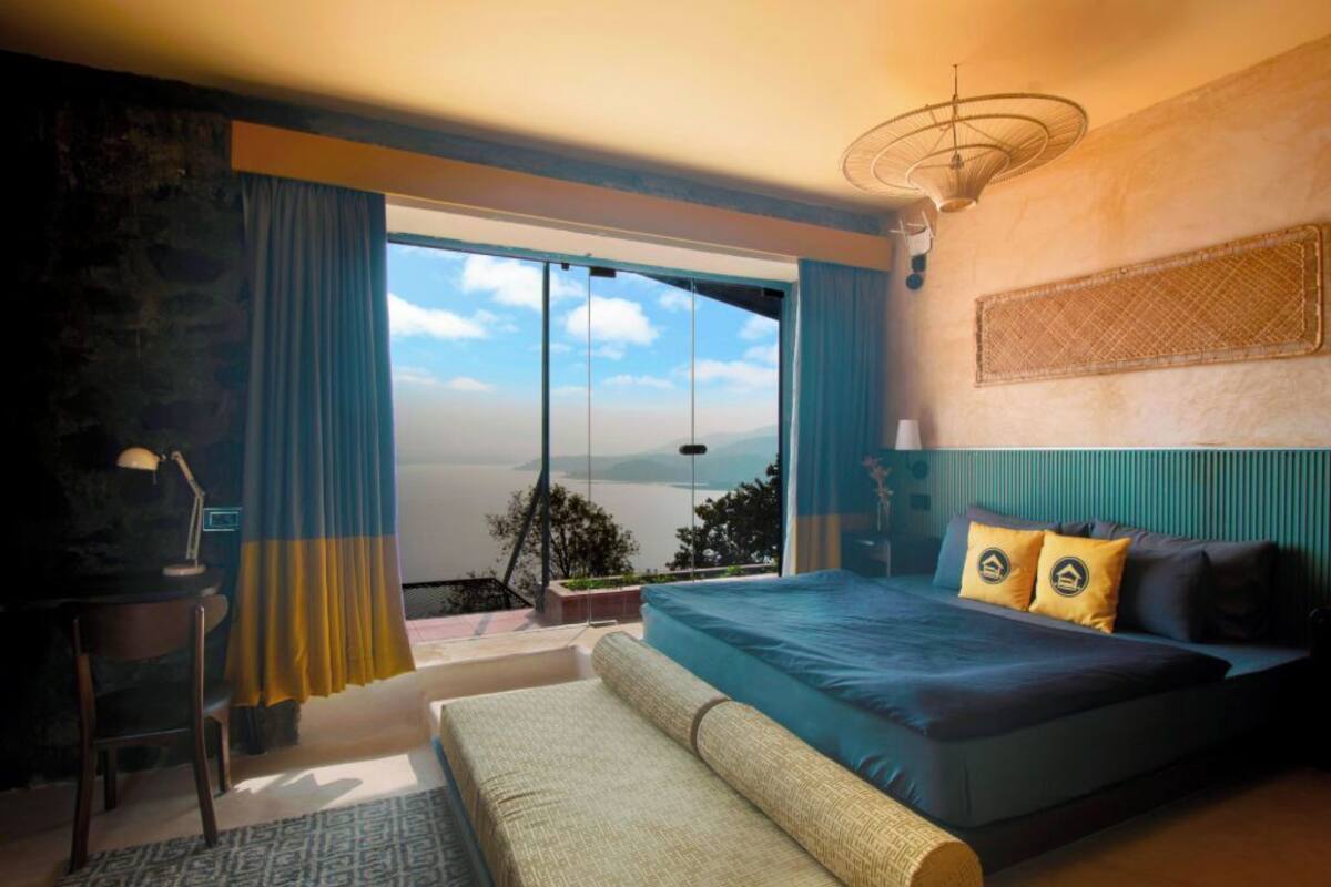 Un dormitorio con una cama grande, un escritorio y vistas al exterior.