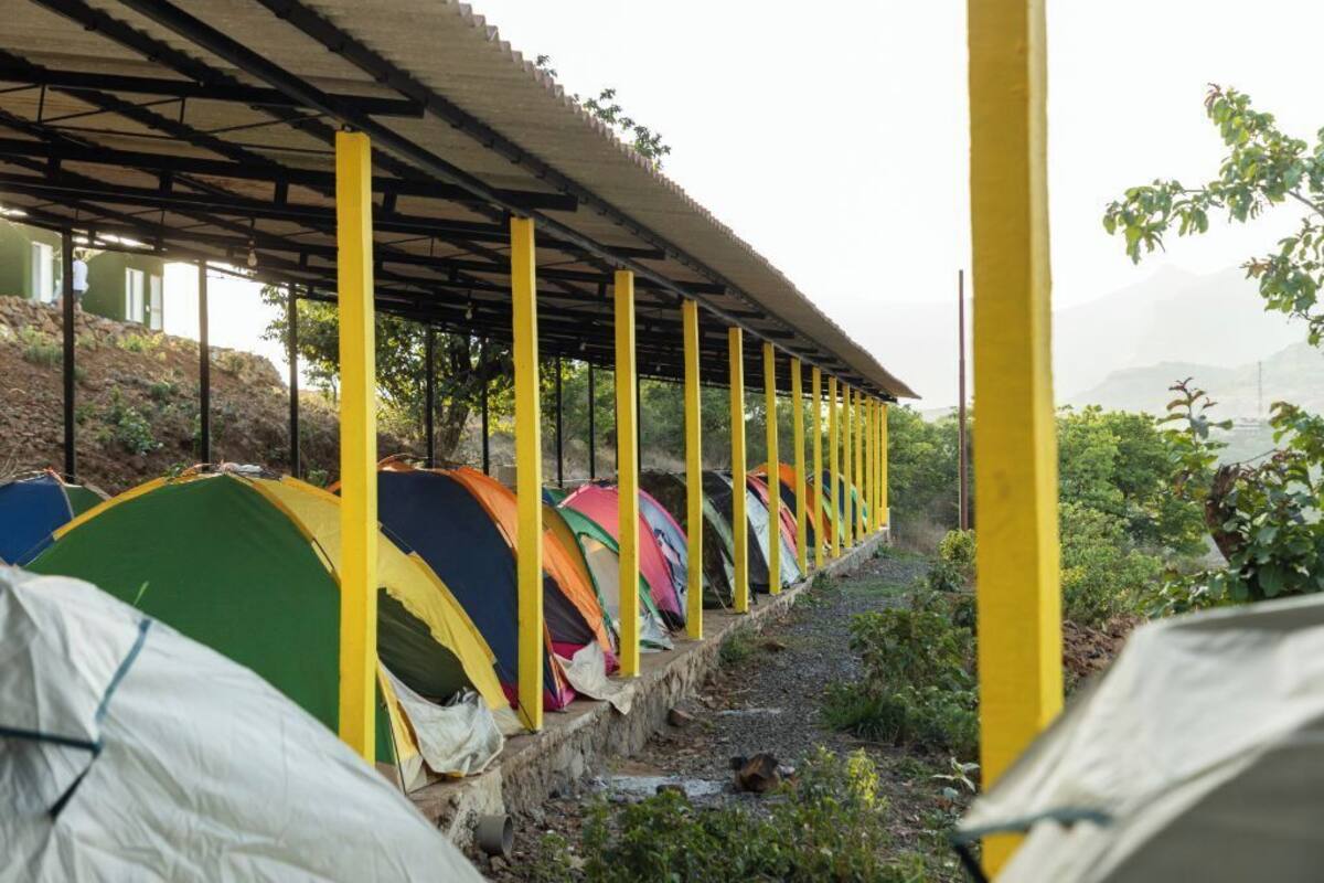 Una hilera de tiendas de colores bajo una estructura cubierta con pilares amarillos.