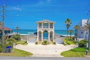 A two-story house with a balcony, a garage, and a view of the ocean.