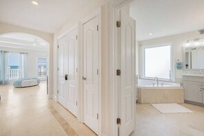 A spacious hotel room with a large window, a bathtub, and a walk-in closet. - High Tide Estate | Team Joseph Ellen (Ponte Vedra Beach)