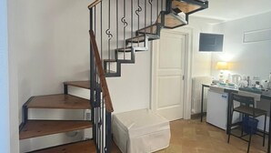 A staircase with wooden steps and metal railings, leading to a room with a white door, a small table, and a chair.