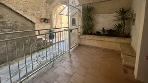 A corridor with stone walls, a metal railing, and potted plants.