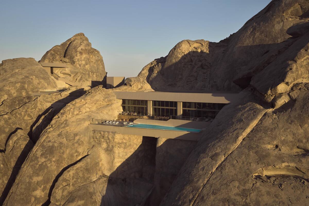 A modern building with a pool, set against a rocky landscape.