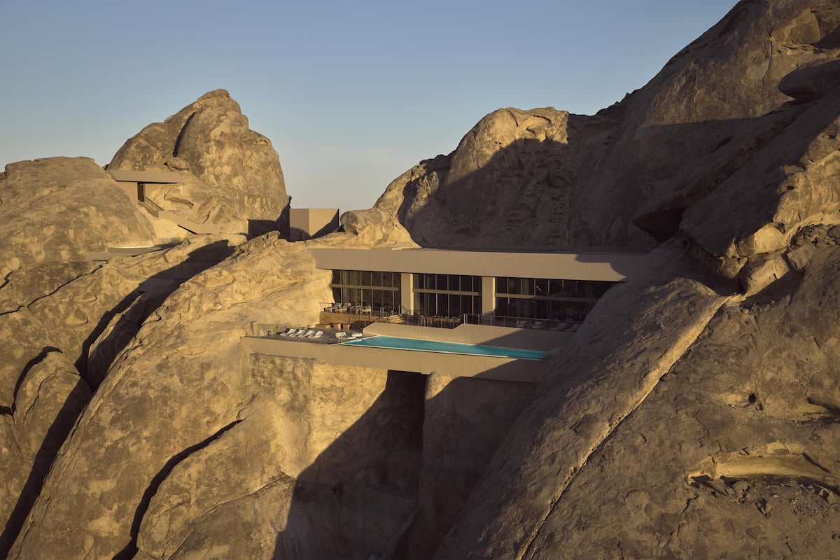 A modern building with a pool, set against a rocky landscape.