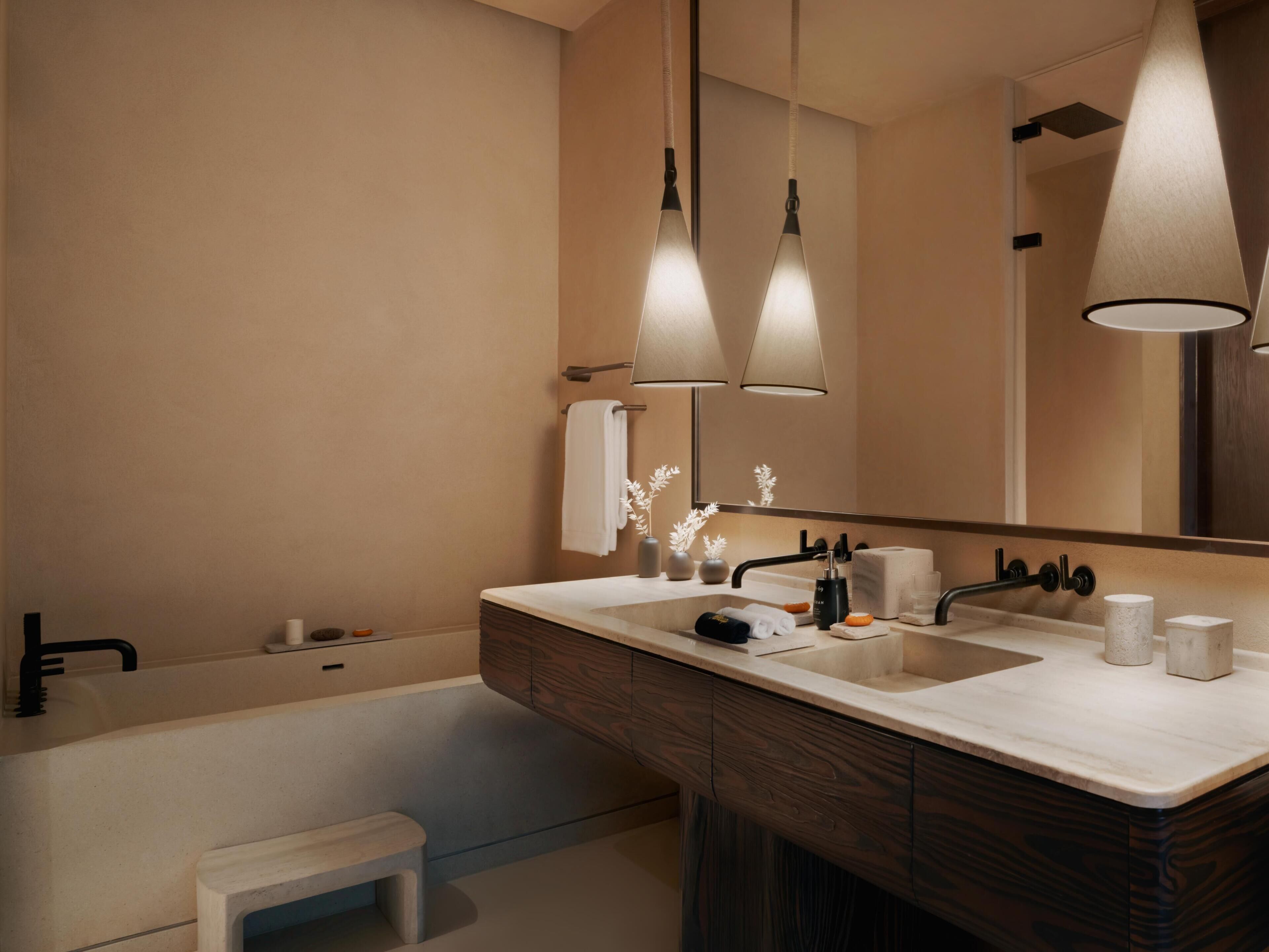 A modern bathroom with a bathtub, two sinks, a vanity, and a large mirror.