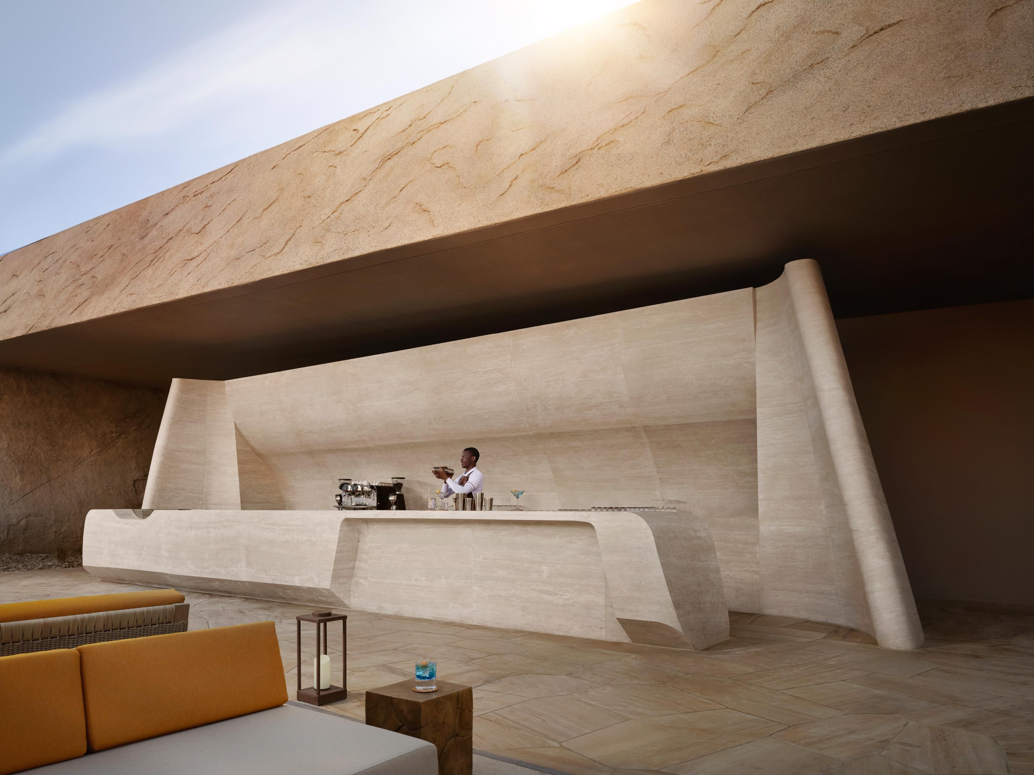An outdoor seating area with a bar and a person preparing a drink.