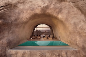 An arched viewing area with a pool, seating, and a view of a mountainous landscape. - Desert Rock Resort (Umluj)